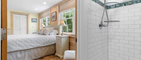 A bedroom with a bed, bedside table, lamp, and window.