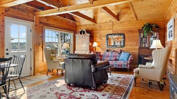 A wooden interior with a sofa, chairs, a table, and a patterned rug.