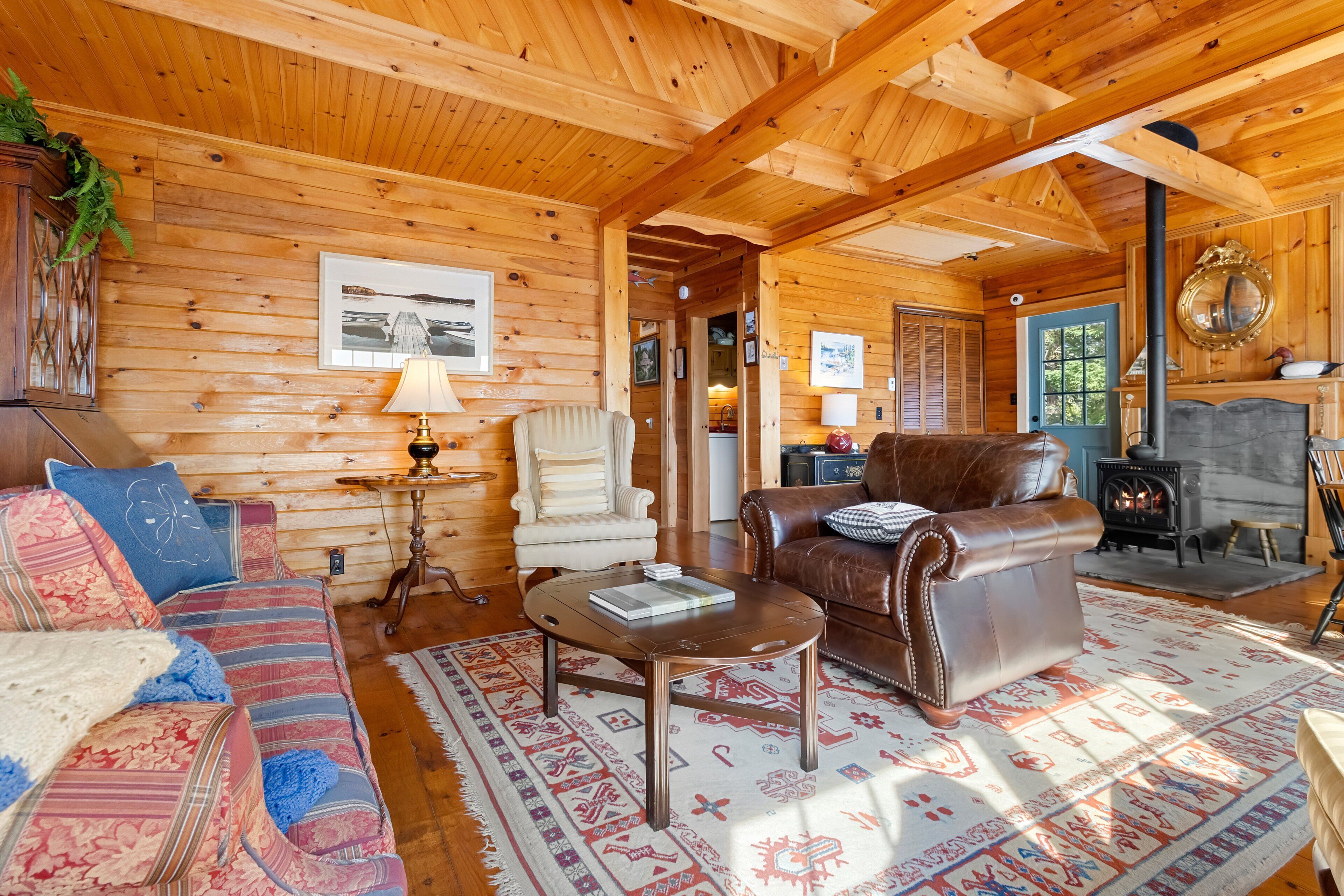 A cozy log cabin interior with a sofa, armchair, and leather couch.