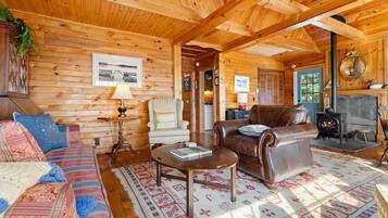 A cozy log cabin interior with a sofa, armchair, and leather couch.