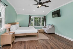 A bedroom with a bed, bedside table, lamp, ceiling fan, and a window with curtains. - Lake Days & Cozy Nights | Lake Murray Getaway (Lexington)