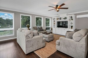 A modern living room with a sectional sofa, a coffee table, and a flat-screen TV. - Lake Days & Cozy Nights | Lake Murray Getaway (Lexington)