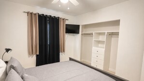 A bedroom with a bed, a ceiling fan, a wardrobe, and a mirror.