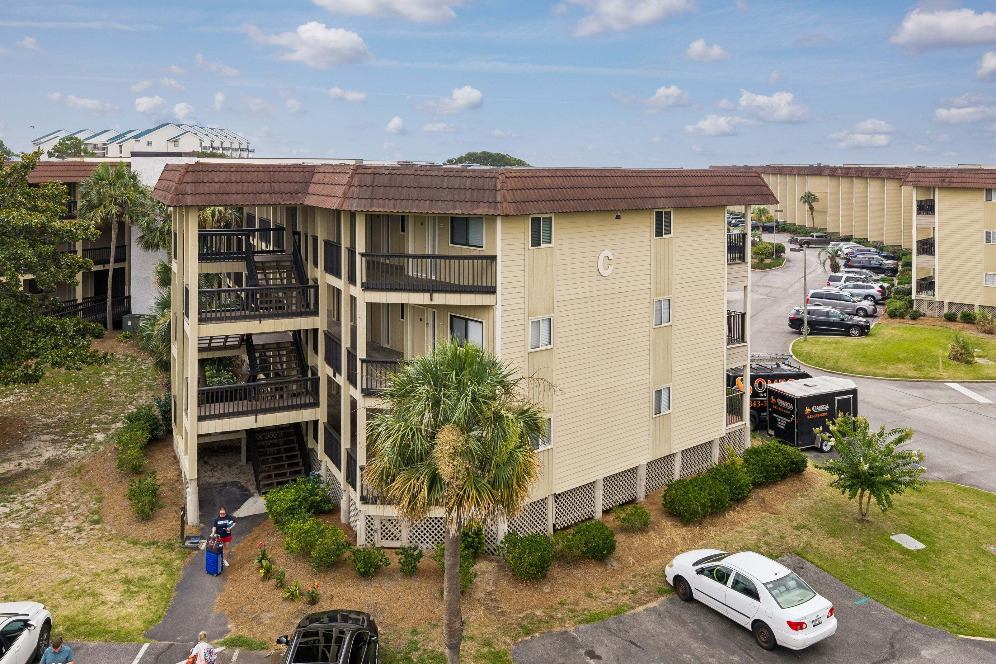 A multi-story hotel with a central courtyard, parking area, and a visible outdoor seating area.