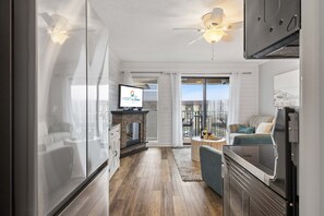 Eine moderne Küche mit Backofen, ein Essbereich mit Tisch und Stühlen sowie ein Wohnzimmer mit Sofa und Fernseher.