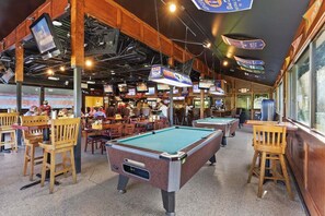 A pool hall with multiple pool tables, wooden chairs, and overhead TVs. - Hilton Head Beach & Tennis Resort , Oceanfront, Tennis, Restaurants, Pickleball! (Hilton Head Island)