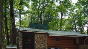 A rustic cabin with a stone exterior, a barbecue grill, and a patio with outdoor seating.