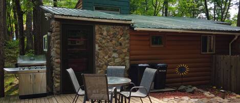 A rustic cabin with a stone exterior, a barbecue grill, and a patio with outdoor seating.