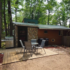 A rustic cabin with a stone exterior, a barbecue grill, and a patio with outdoor seating.