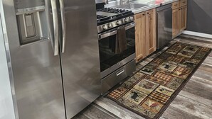 A kitchen with a stainless steel refrigerator, a stove, and wooden cabinets.