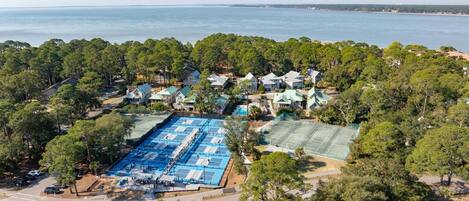 An aerial view of a coastal residential area with houses, a tennis court, and a swimming pool.