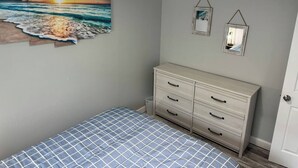 A bedroom with a bed, a dresser, a wall-mounted artwork, and a ceiling light. - Bayfront! 2 BR/2 BA Upper condo [2nd/top floor]- Spectacular Bay view! [no dogs] (Brigantine)