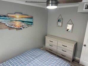 Une chambre à coucher comprenant un lit, une commode, une œuvre d’art accrochée au mur et un luminaire au plafond.