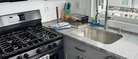 A modern kitchen with a gas stove, microwave, and stainless steel sink.