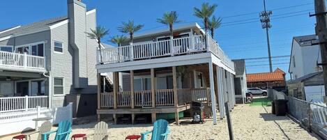 Una propiedad frente a la playa con terraza cubierta, mobiliario exterior y zona de arena.