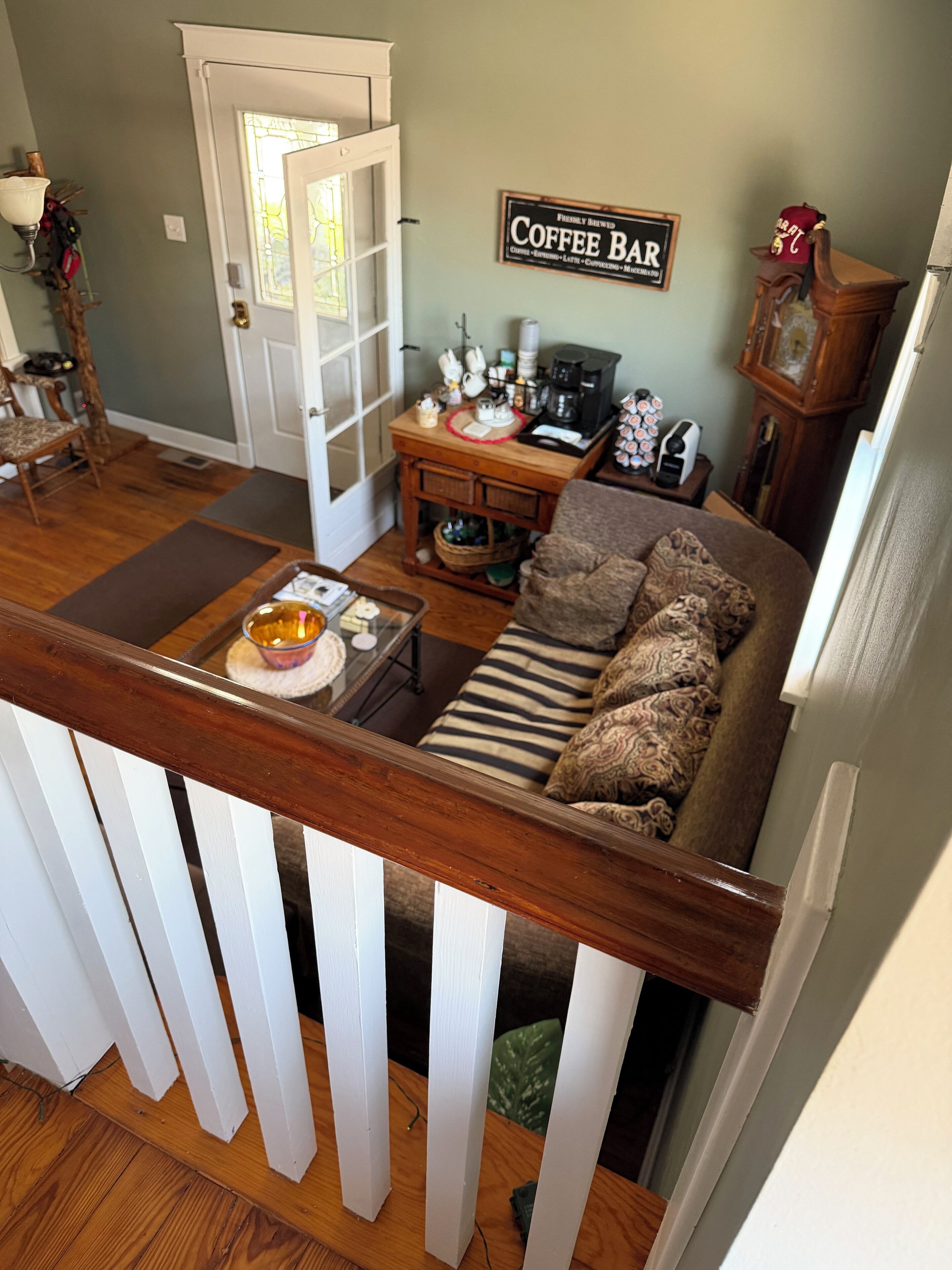 A living room with a sofa, coffee table, and a coffee bar sign on the wall.