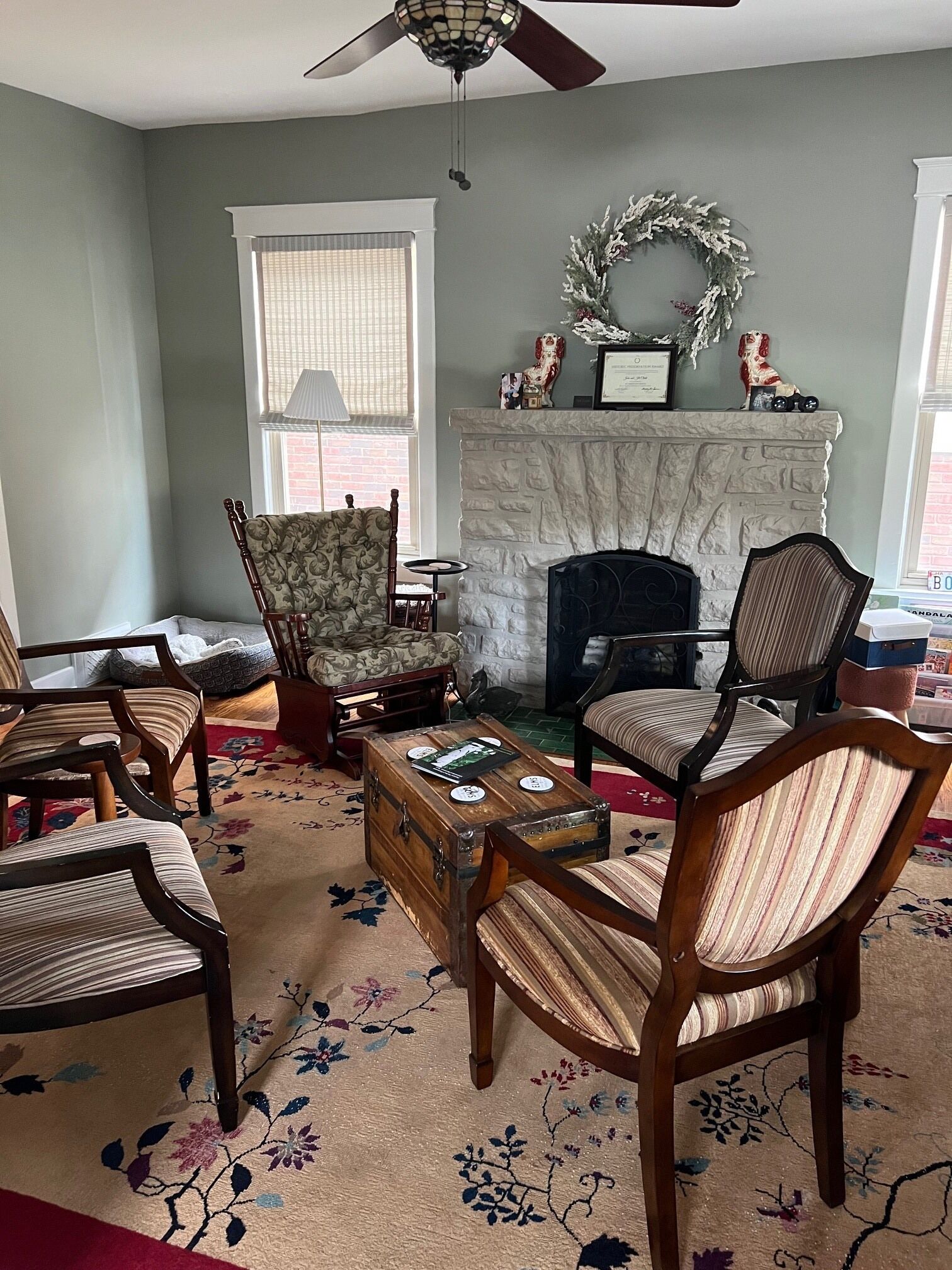 A living room with a fireplace, multiple chairs, a coffee table, and a decorative wreath.