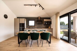 A modern kitchen with a dining area, featuring a large window, a built-in oven, and a dining table set for four. - Villa Casa Dvori (Istria - Valtura) (Valtura)