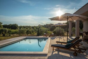 A swimming pool with lounge chairs and umbrellas, surrounded by a garden and trees. - Villa Casa Dvori (Istria - Valtura) (Valtura)