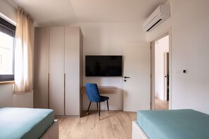 A bedroom with two beds, a desk, a chair, a TV, and an air conditioning unit. - Villa Casa Dvori (Istria - Valtura) (Valtura)
