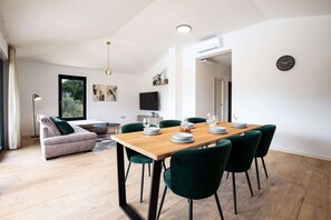 A modern dining area with a wooden table set for six, surrounded by green upholstered chairs. - Villa Casa Dvori (Istria - Valtura) (Valtura)