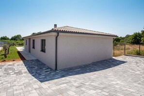 A single-story building with a tiled roof, a paved patio, and a small garden area. - Villa Casa Dvori (Istria - Valtura) (Valtura)