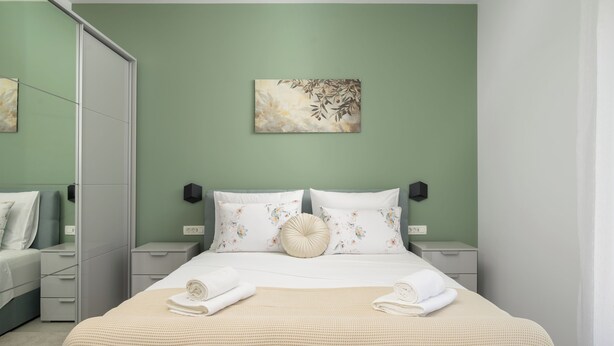 A bedroom with a bed, two bedside tables, a nightstand, a mirror, and a wall-mounted artwork. - Villa Luen (Istria - Cukrići) (Cukrići)