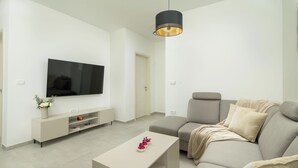 A modern living room with a flat-screen TV, a sofa, a coffee table, and pendant lighting. - Villa Luen (Istria - Cukrići) (Cukrići)