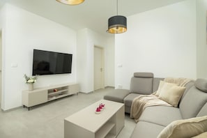 A modern living room with a flat-screen TV, a sofa, a coffee table, and pendant lighting. - Villa Luen (Istria - Cukrići) (Cukrići)