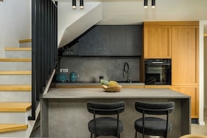 A modern kitchen with a central island, bar stools, and a staircase. - Villa Casa Abete (Istria - Svetvinčenat) (Svetvinčenat)