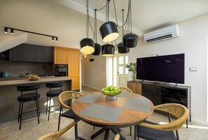 A modern kitchen with dark cabinets, a built-in oven, and a dining area with a round table and chairs. - Villa Casa Abete (Istria - Svetvinčenat) (Svetvinčenat)