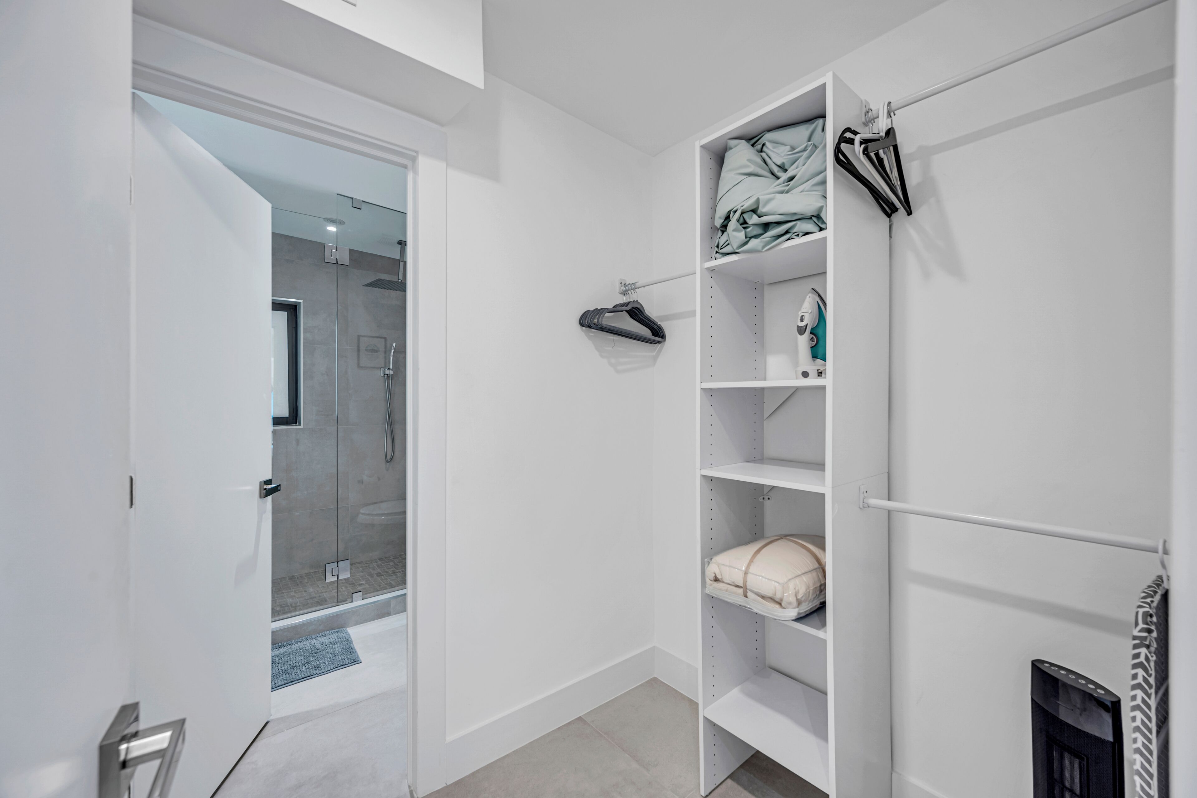 Une salle de bain moderne avec une douche à parois de verre, un meuble-lavabo blanc et des étagères intégrées.