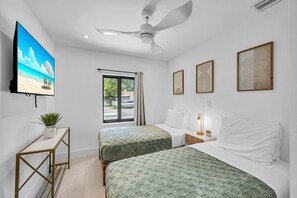 Ein Hotelzimmer mit zwei Betten, einem Fernseher, einem Deckenventilator und Bildern an den Wänden.