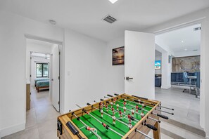 Ein modernes Zimmer mit einem Kicker, einem Gemälde und Blick ins Freie.