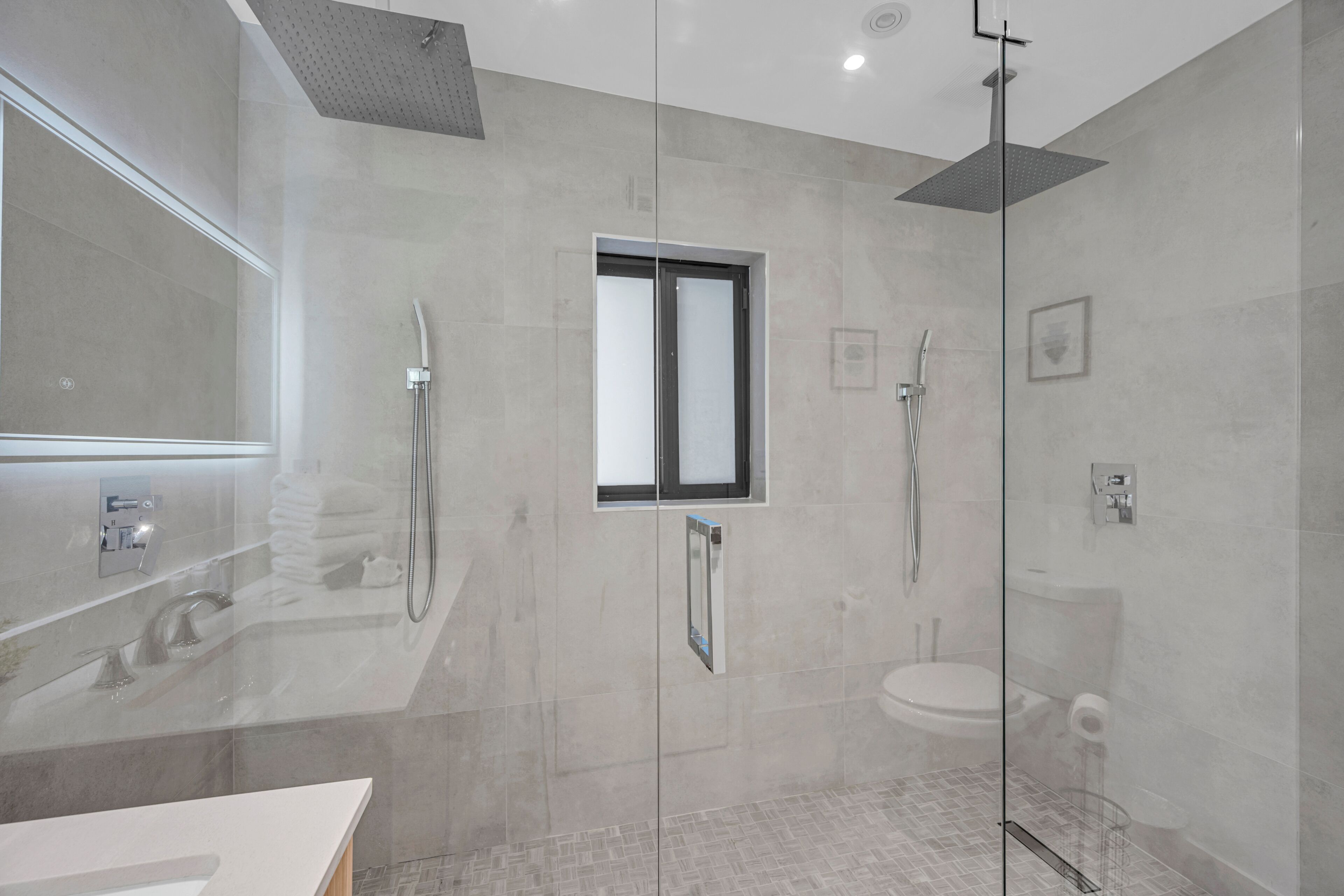 A modern bathroom with a glass-enclosed shower, a built-in sink, and a large mirror.