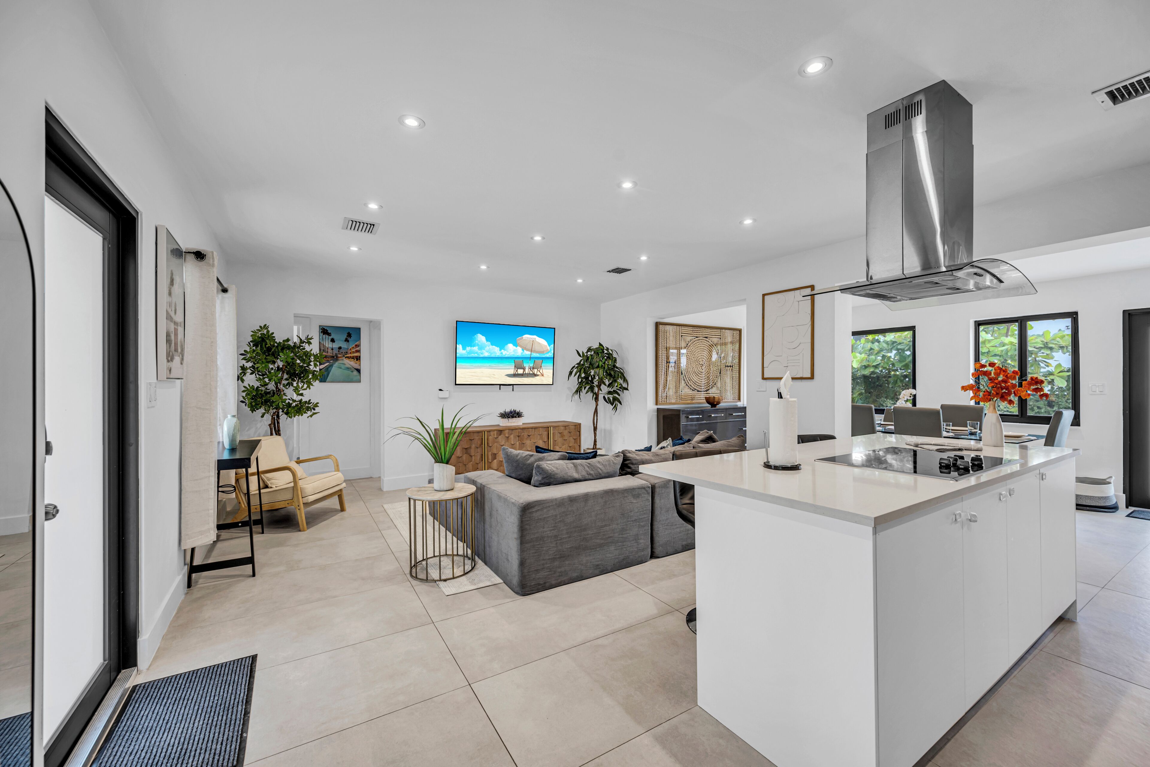 A modern kitchen with a central island, a dining area with a view, and a living space with a sofa and a coffee table.