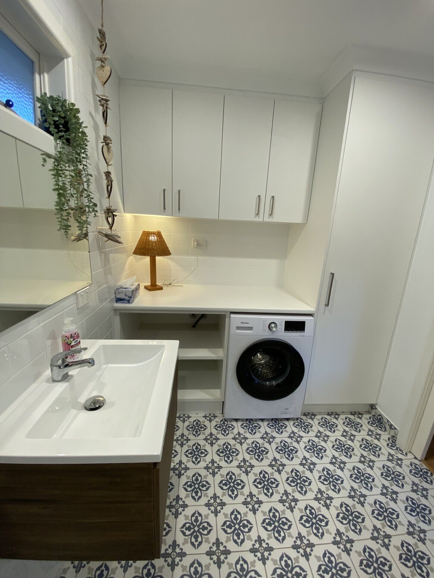Ein kleines Badezimmer mit Waschbecken, Waschmaschine und Spiegel.