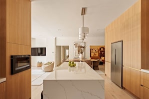 A modern kitchen with a central island, built-in oven, and stainless steel refrigerator.