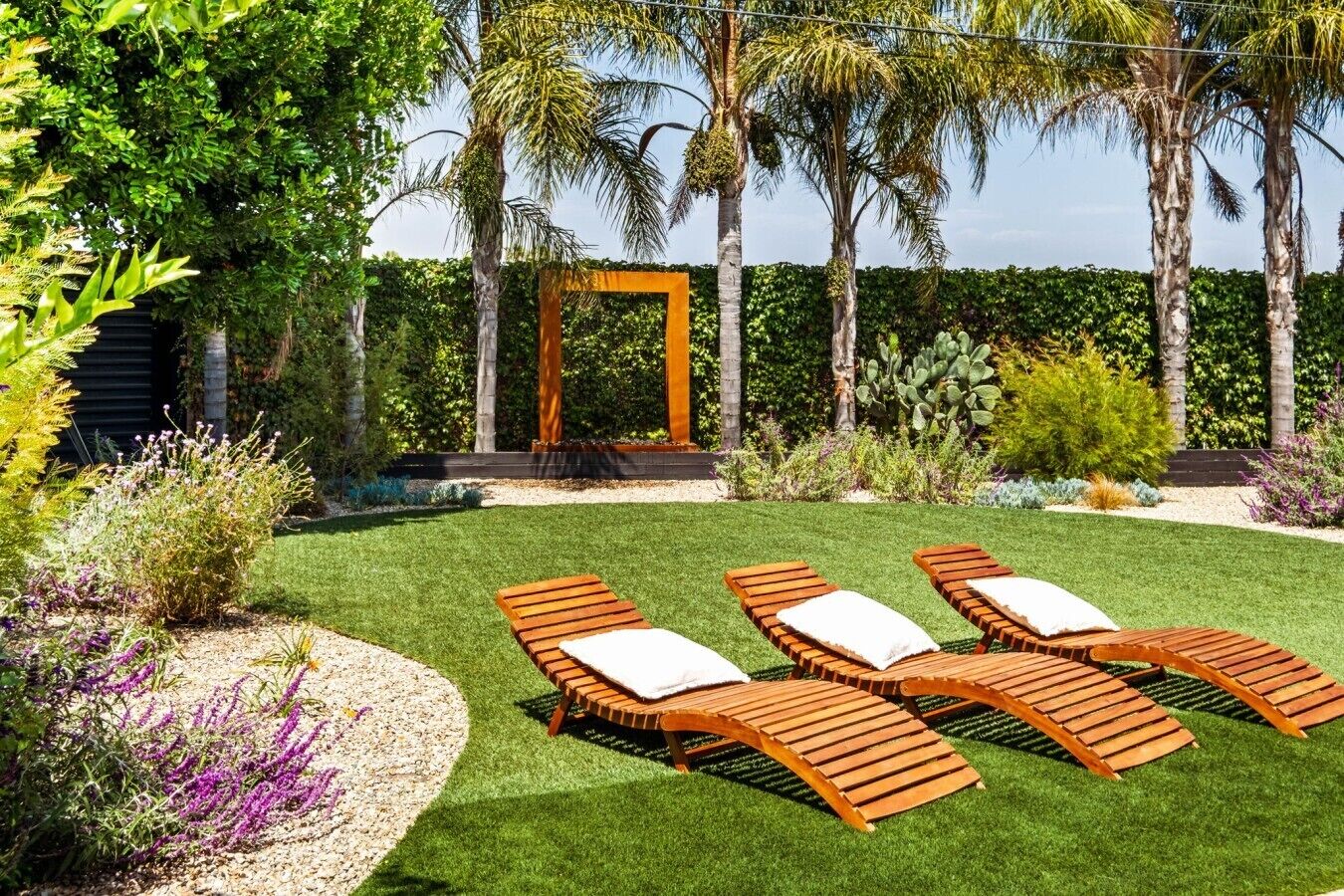 A garden with a wooden pergola, a lawn, and a seating area with lounge chairs.