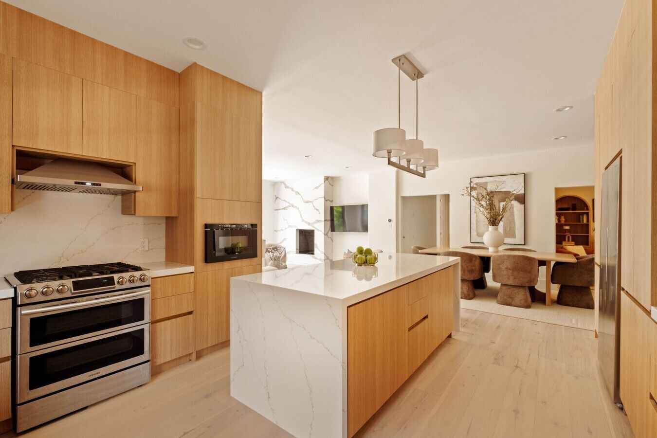 Una cocina moderna con una isla central, hornos integrados y muebles de madera.