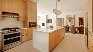 A modern kitchen with a central island, built-in ovens, and wooden cabinetry.