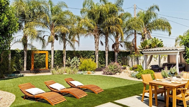A backyard with a patio area, a pergola, and a seating arrangement.