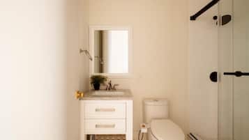 Un baño con lavamanos, espejo y retrete blancos.