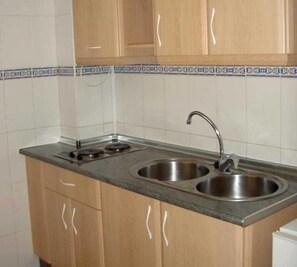 A kitchen with two sinks, a stove, and wooden cabinets. - Santa Clara (Alhaurin de la Torre)
