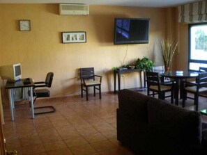 A room with a flat-screen TV mounted on the wall, a desk with a computer, a chair, a sofa, and a dining table with chairs. - Santa Clara (Alhaurin de la Torre)