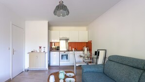 Ein modernes Wohnzimmer mit einer Couch, einem Couchtisch mit Dekoration und Blick in den Küchenbereich.