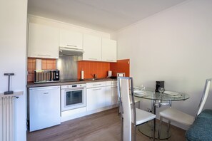 A modern kitchen with white cabinets, a stainless steel range hood, and a built-in oven. - Appartement Les Heures Claires avec Terrasse - Welkeys (Mandelieu-la-Napoule)