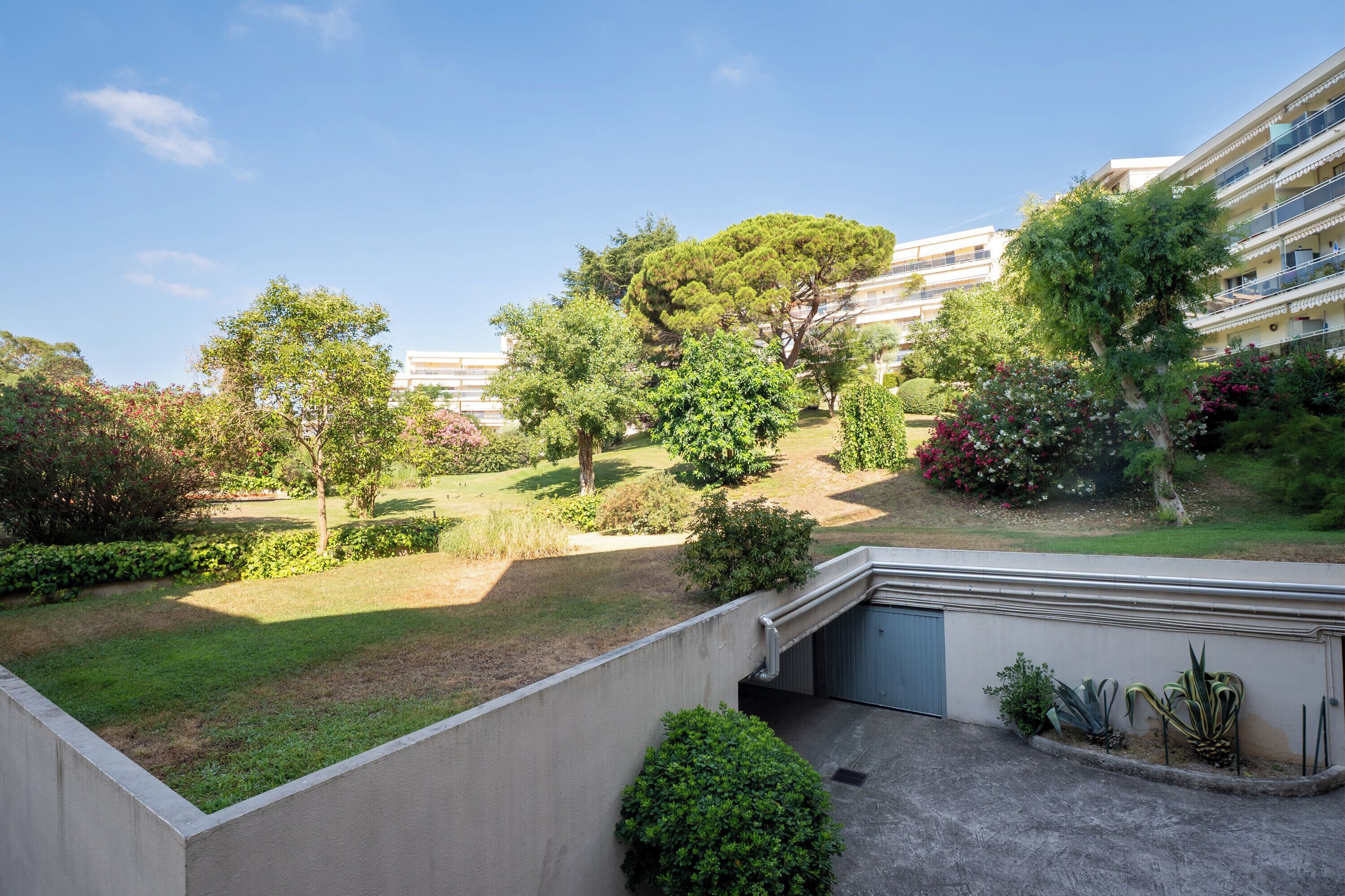 A residential area with a well-maintained garden, a pathway, and a building with balconies.