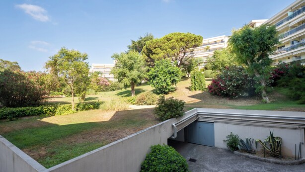 Ein Wohngebiet mit gepflegtem Garten, einem Weg und einem Gebäude mit Balkonen.
