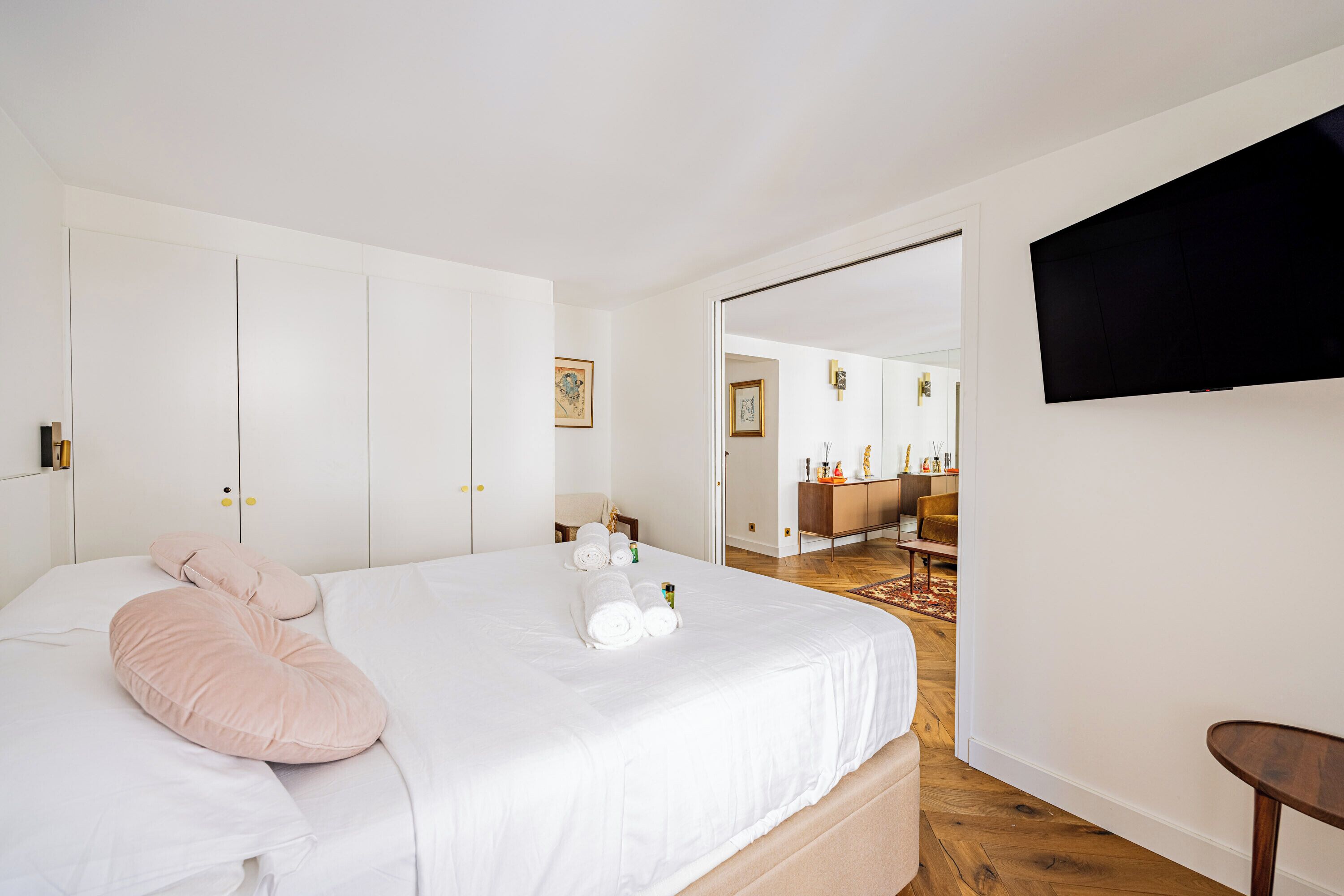 Une chambre d’hôtel avec un lit, un téléviseur fixé au mur et une salle de bain visible à travers une porte ouverte.